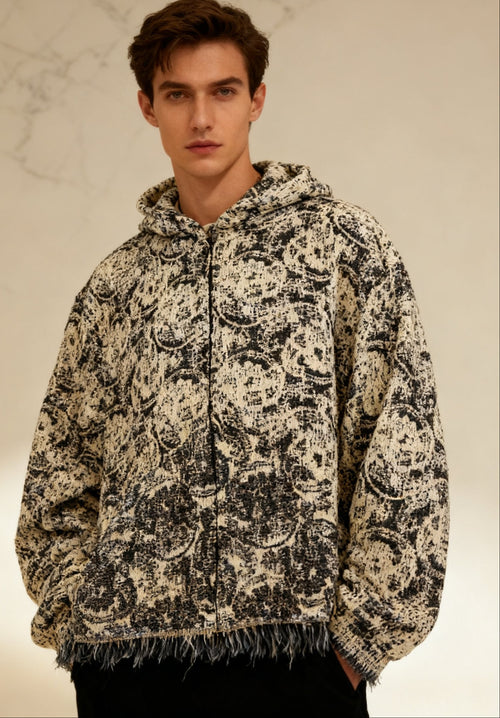 Man wearing a patterned hoodie against a neutral background